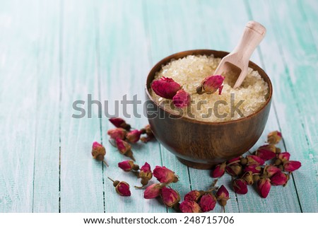 Spa setting with sea salt and flowers on aqua painted wooden boards. Selective focus is salt in bowl.