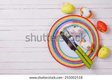 Easter table setting.  Colorful plates, cutlery,eggs, bird. Selective focus. Place for text.