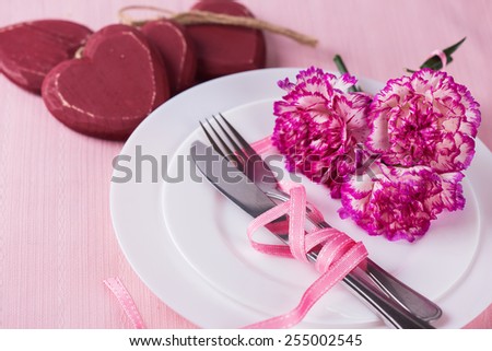 Romantic table setting. Plate, flowers, cutlery, decorative hearts. Selective focus.