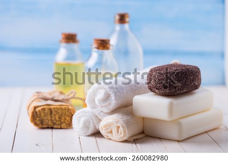 Spa setting with soap, towels, pumice and aroma oil on  painted wooden boards. Selective focus is on towels.