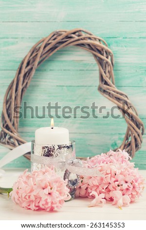 Fresh hyacinths flowers, candle, decorative heart on white wooden background against turquoise wall. Selective focus. Romantic background. Toned image.