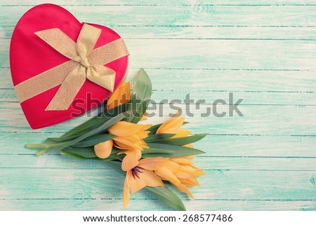 Postcard with fresh  spring yellow tulips flowers and gift box on turquoise painted wooden planks. Selective focus. Place for text. Toned image.