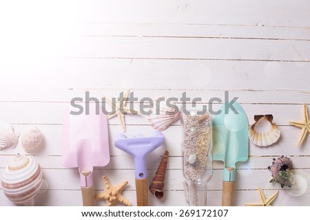 Tools for kids for playing in sand and sea objects in ray of light on white  painted wooden background. Place for text. Vacation background.