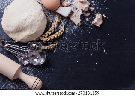 Dough and ingredients for it - eggs, flour, yeast on dark slate background. Selective focus. Place for text.