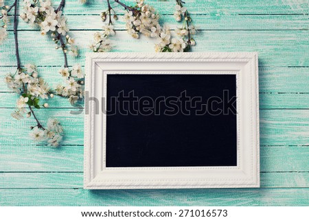 Background with white  spring flowering branches of trees  and empty blackboard for text on turquoise painted wooden planks. Selective focus. Place for text. Toned image.