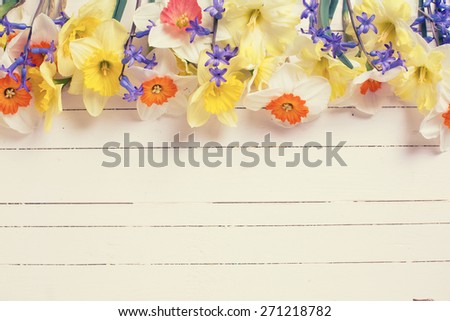 Border from colorful yellow, orange and blue spring flowers  on white  painted wooden planks. Selective focus. Place for text. Toned image.