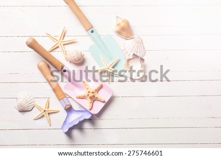 Tools for kids for playing in sand and sea object  in ray of light on white  painted wooden background. Place for text. Vacation  background.