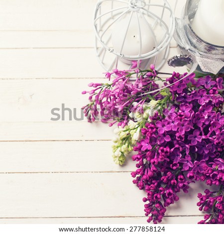 Fresh white and violet lilac flowers and candles on white painted wooden planks. Selective focus. Place for text. Square image.