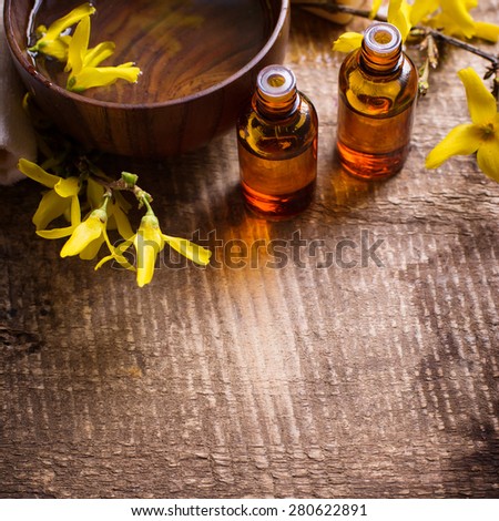 Spa setting. Essential aroma oil in bottles , water in bowl, yellow flowers on aged wooden background. Selective focus. Place for text.  Square image.