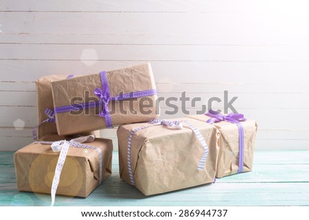 Wrapped boxes with presents  in ray of light on turquoise painted wooden planks against white wall. Selective focus. Place for text.