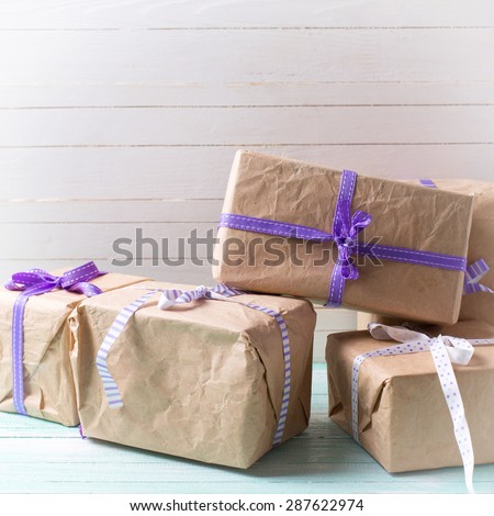 Wrapped boxes with presents on turquoise painted wooden planks against white wall. Selective focus. Square image.