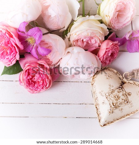 Sweet pastel roses, clematis flowers and decorative heart on white  wooden background. Place for text. Selective focus. Square image.
