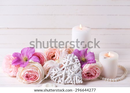 Decorative heart, pink roses  and violet clematis flowers and candles on white  wooden background.  Selective focus. Place for text.