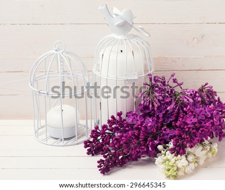 Fresh white and violet lilac flowers and candles on white painted wooden planks. Selective focus. Place for text.  Toned image.