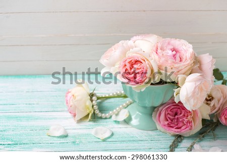 Background with sweet pink roses flowers  on turquoise painted wooden planks against white wall. Place for text. Selective focus.