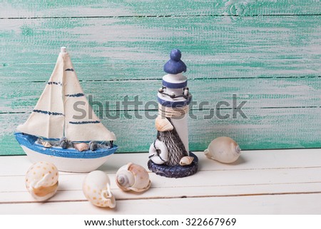 Decorative lighthouse,  sailing boat and marine items on wooden background. Sea objects on wooden planks. Selective focus in on boat. Place for text.