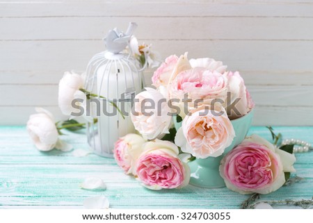 Background with sweet pink roses in vase and candle  on turquoise painted wooden planks against white wall. Shabby chic.  Selective focus.