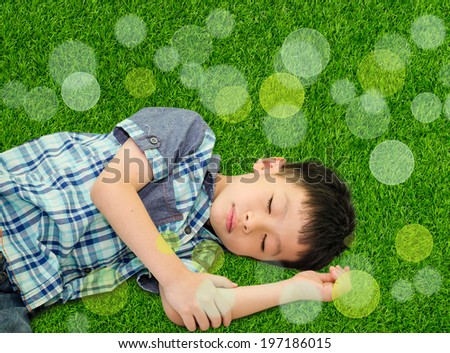 Happy Asian boy sleeping on green grass outdoors