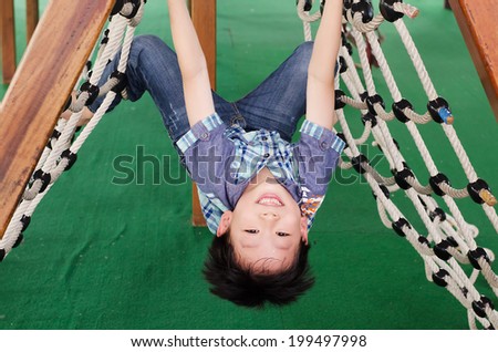 Young Asian boy climbing rope on indoor playground