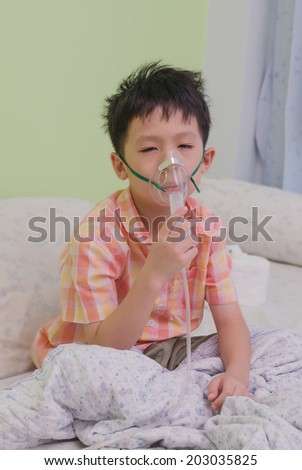Sick Asian boy with a mask for inhalations