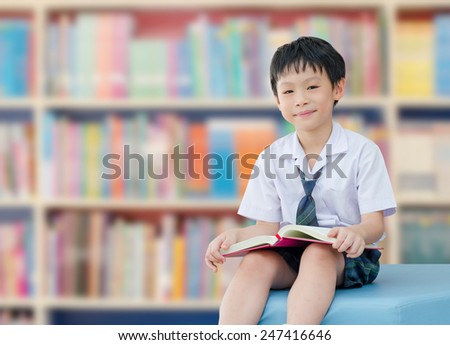 Asian boy student in uniform reading book in school library