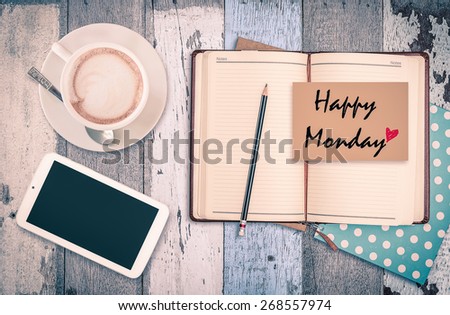 Happy Monday on notebook with smart phone and coffee cup on wood table