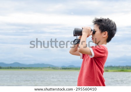 Young Asian boy using binoculars near by the lake
