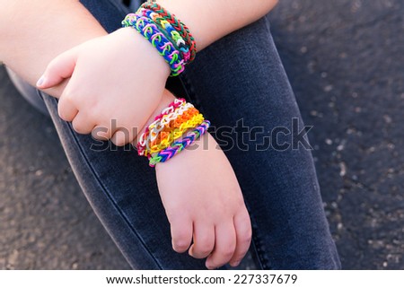 Young girl wearing loom bracelets, Young fashion, outdoors, friendship, crafts, and lifestyle concept. Bright tones. Shallow depth of field.