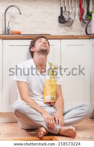 Tired man sitting on the floor at the kitchen