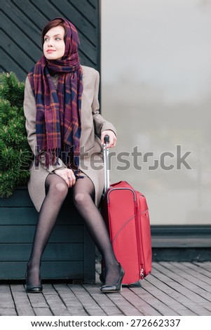 Classy woman with suitcase is waiting for someone