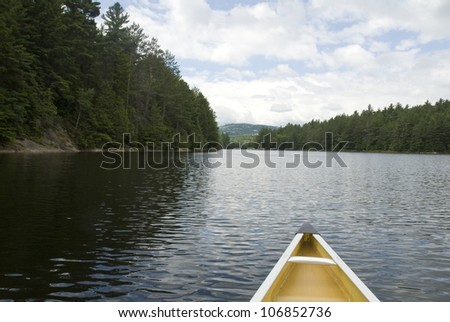 The nose of a canoe points the way into a distant passage in a wilderness lake.