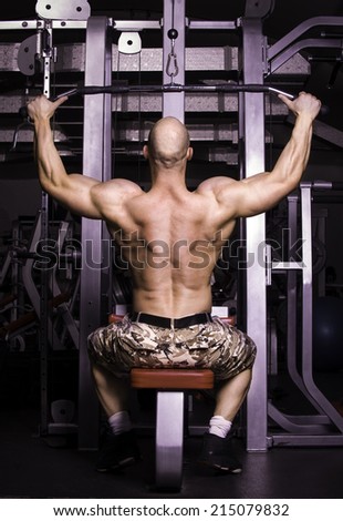 Fit man on lat pulldown machine at the health club. Work out on Pulldown Weight Machine