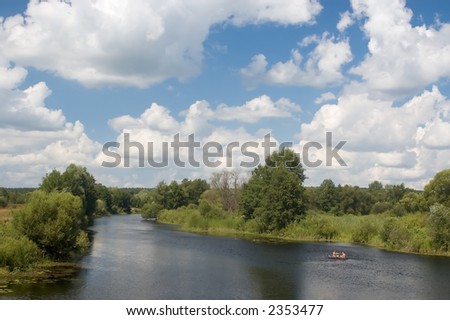 calm river landscape with overgrown bank and clouds