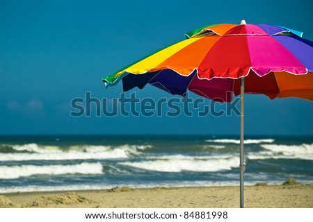 Brightly colored beach umbrella with waves and blue sky in the background