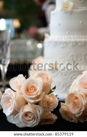 Bouquet of apricot roses with a white wedding cake in the background
