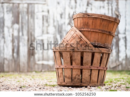 Three empty apple orchard baskets stacked in front of the barn