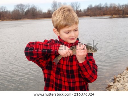 Cute boy and a Rainbow Trout fish caught fly fishing at a lake