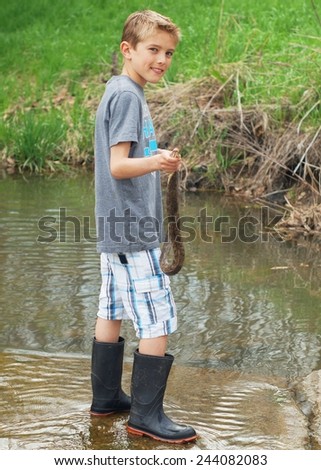 Boy catching and holding a large wild snake that is trying to bite, Nerodia sipedon