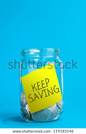A jar of coins, with keep saving reminder note inside the jar.