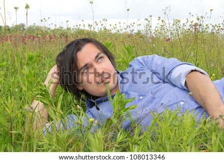 Man lying on the grass with a blade of grass in his mouth