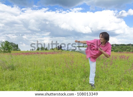 Man practicing karate kick in spring field