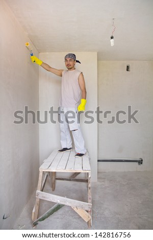 Young man painting wall with painting roller