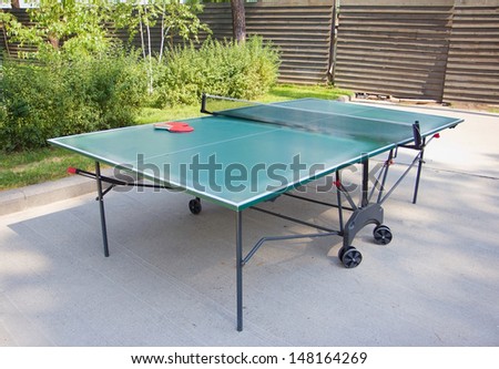 Green ping-pong table and rackets outdoors