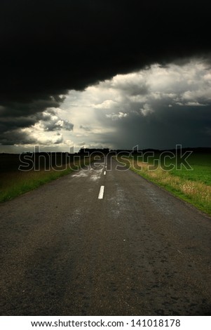 Asphalt road and dark storm clouds over it