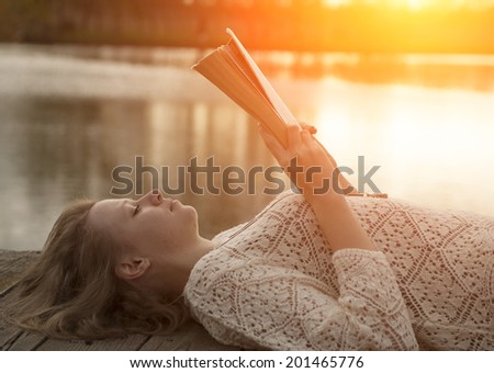 Girl reading a book in sunset