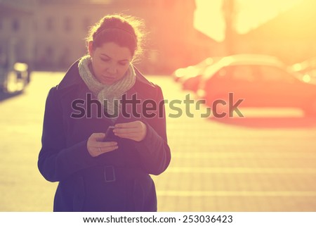 Vintage effected photo of woman use mobile phone in the city