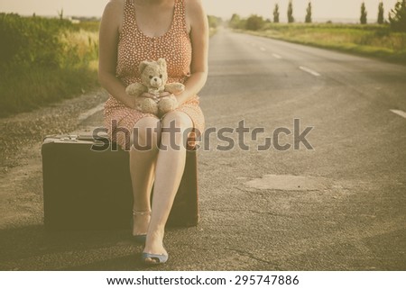 Traveler woman on the road with retro suitcase and teddy bear