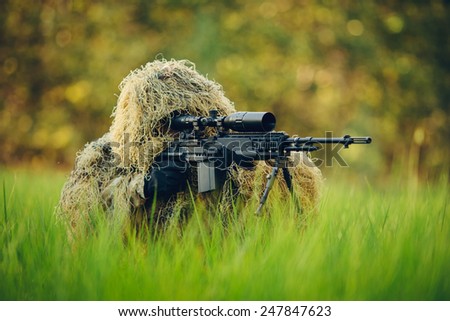 Sniper in the grass looking through the scope