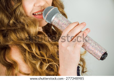 portrait of a beautiful elegant girl singer  with long hair with a microphone in his hand singing a song