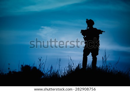 Silhouette of military soldier or officer with weapons at night. shot, holding gun, blue colorful sky, background